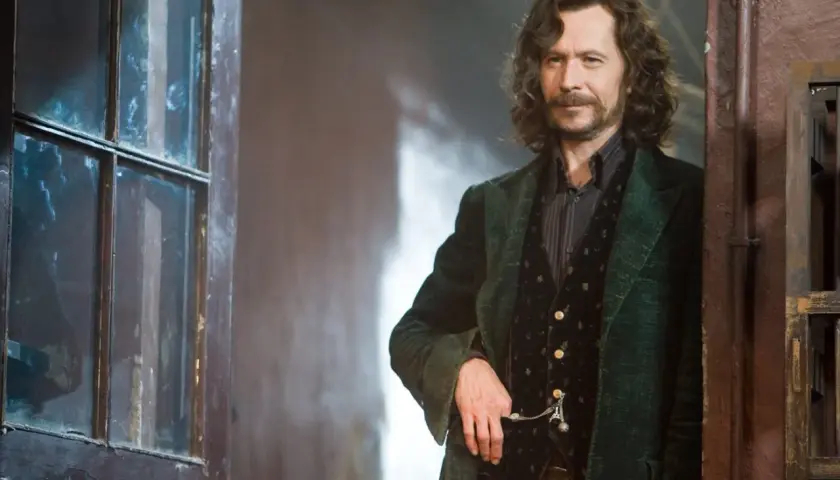 Gary Oldman jako Syriusz Black w Harry Potterze, stojący obok drzwi z szybą.