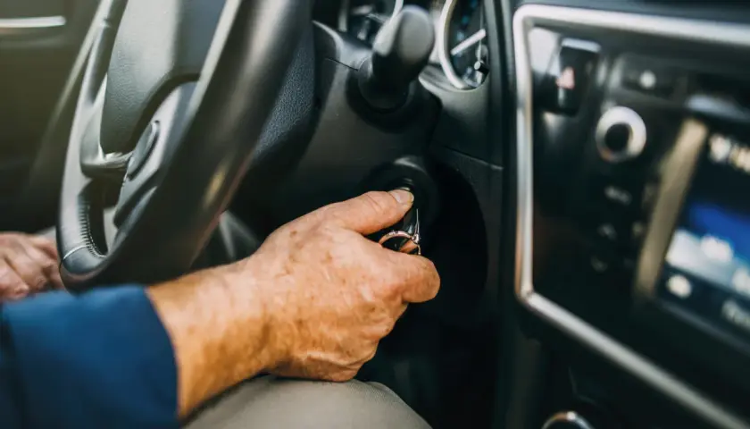 Mano insertando llave en el encendido. Al poner en marcha un motor de gasolina es conveniente tener el coche listo.