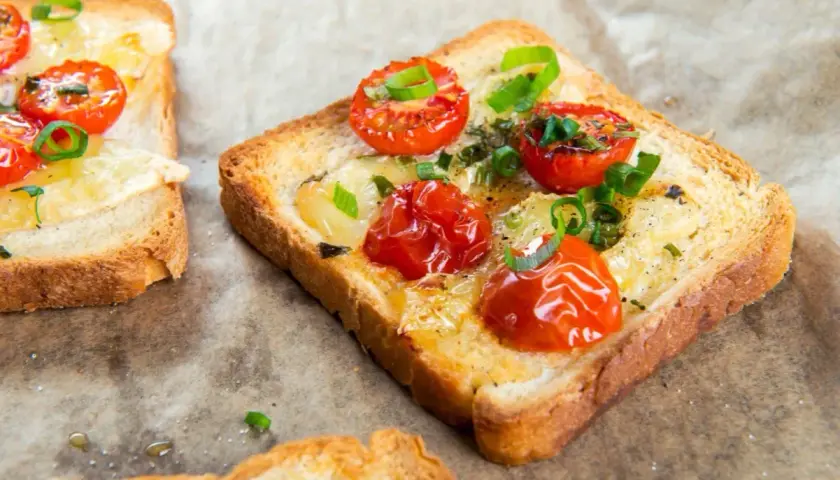 Chrupiące tosty z pomidorkami i serem – idealna lekka kolacja. Posypane szczypiorkiem i przyprawami.