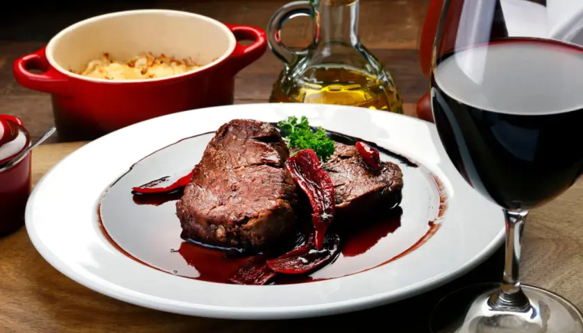 Un plat de viande rouge en sauce, accompagné d'une purée gratinée et d'un verre de vin. Parfait pour savoir que manger avec un sancerre rouge.