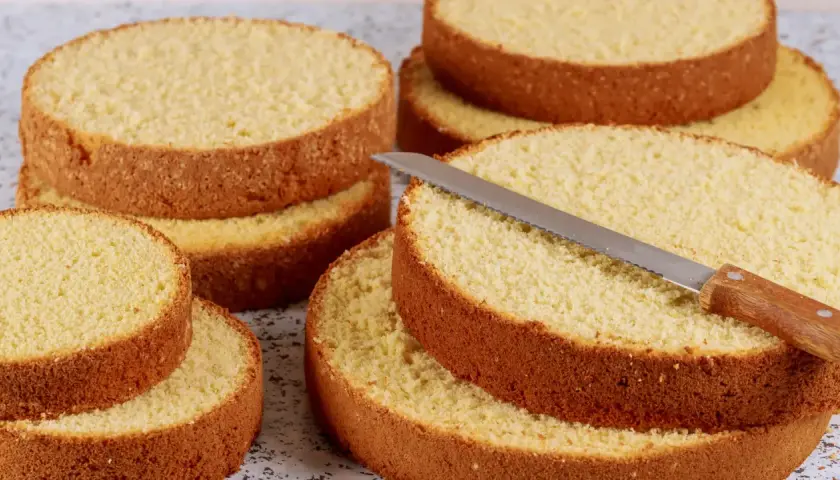 Dischi di pan di spagna dorati e soffici, pronti per essere farciti. Un coltello da pane è appoggiato su uno strato.