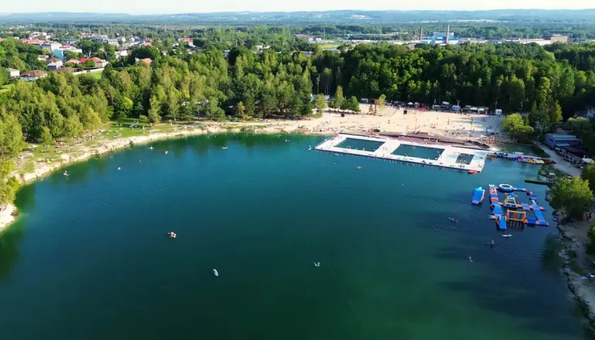 Letni dzień nad wodą w Trzebini. Ludzie odpoczywają na plaży i pływają w jeziorze, które przypomina Balaton.