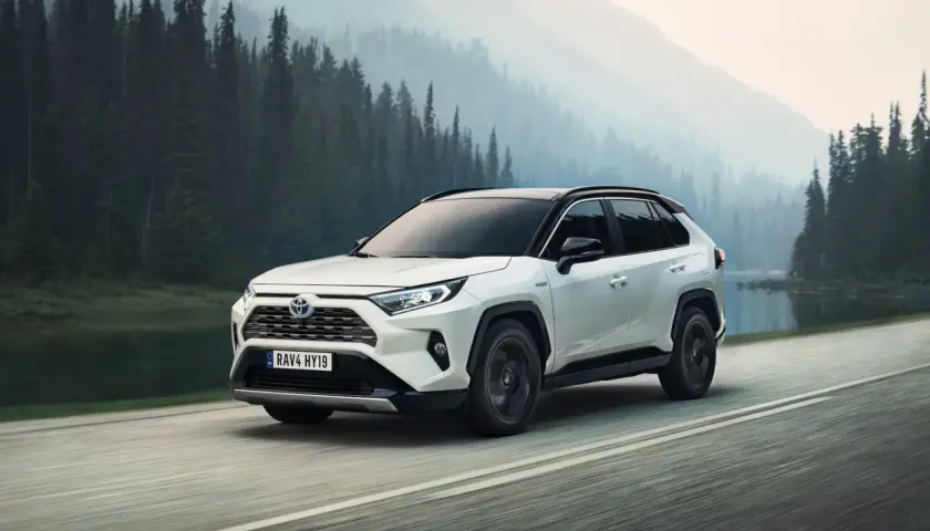 Toyota RAV4 Hybrid, l'auto più venduta al mondo, sfreccia su una strada panoramica tra foreste nebbiose e montagne.