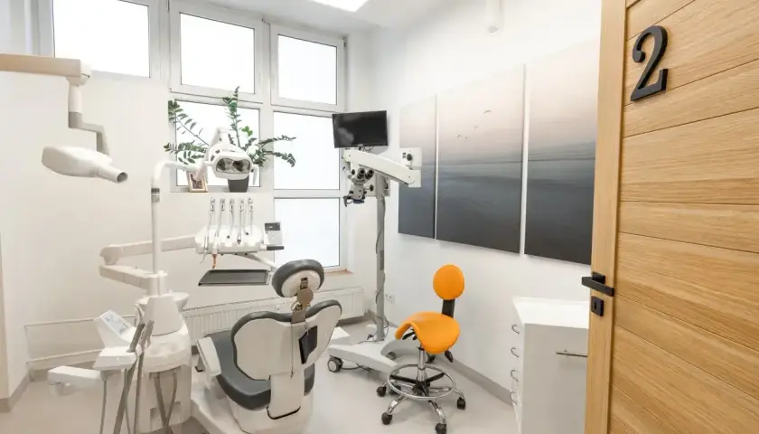 Nowoczesny gabinet stomatologiczny z fotelem, mikroskopem i drzwiami z numerem 2.