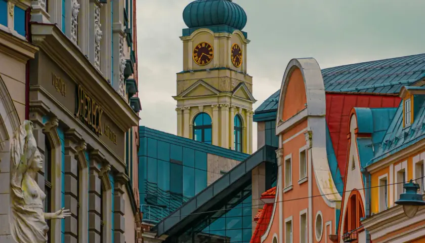 Architektura Rygi zachwyca. Zobaczysz tu zabytkowe kamienice i nowoczesne budynki, a w oddali wieżę zegarową.