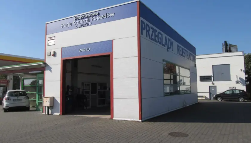 Budynek stacji kontroli pojazdów z napisem "Przeglądy Rejestracyjne" i otwartą bramą wjazdową.