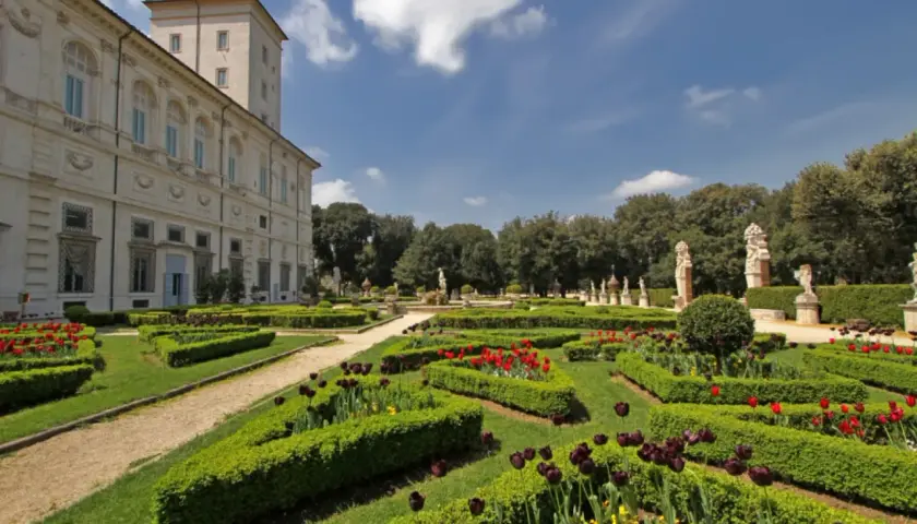 Jardins à la française de la Villa Borghese, avec des parterres de tulipes rouges et noires, des haies taillées et des statues.