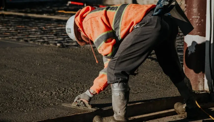 Robotnik w pomarańczowej kamizelce wygładza świeżą wylewkę. Zastanawiasz się, ile worków wylewki na 1m2 potrzeba?