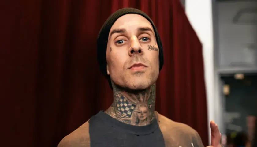 Travis Baker w czarnej czapce beanie, z tatuażami na twarzy i szyi, w tym wizerunkiem Marilyn Monroe.