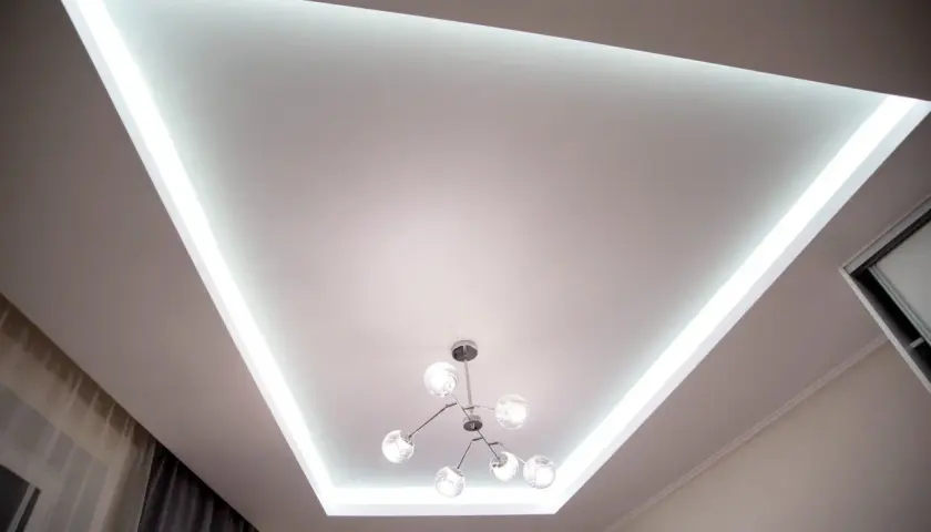 Nowoczesny sufit napinany z podświetleniem LED tworzy niepowtarzalne inspiracje dla wnętrz. Stylowa lampa dodaje elegancji.