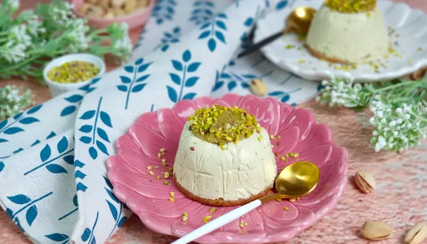 Delizioso semifreddo al pistacchio, guarnito con granella e crema di pistacchi, servito su un piatto rosa.