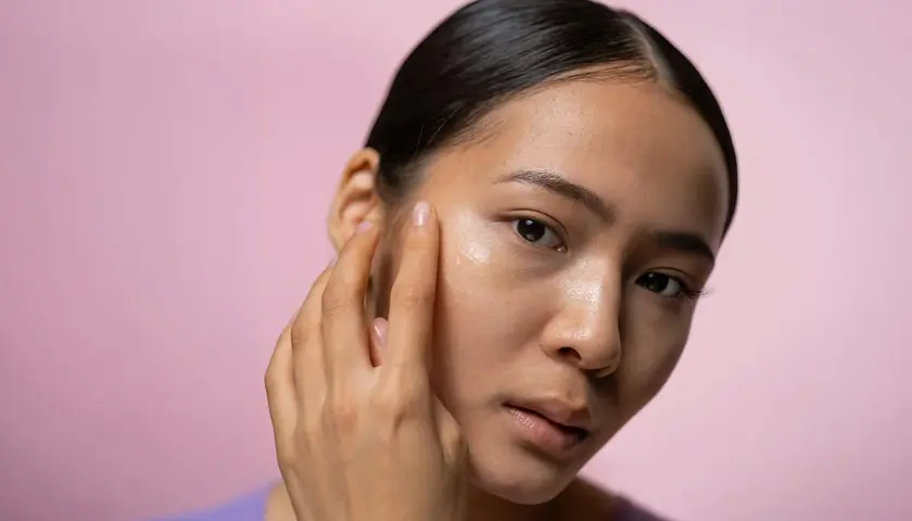 En kvinna applicerar en kräm i ansiktet, kanske en retinolkräm för ett strålande retinol ansikte.