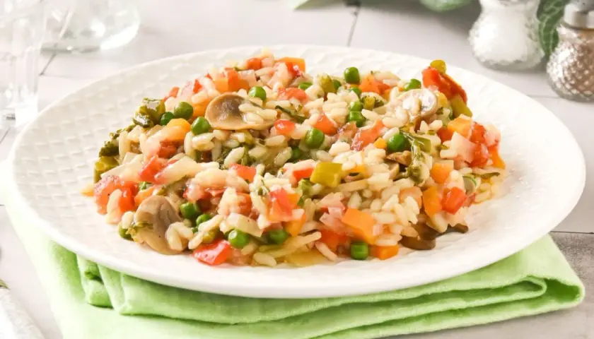 Un cremoso risotto de verduras con guisantes, champiñones y tomate.