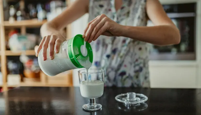 Persona sirve kéfir en un vaso. ¿Cuándo tomar kéfir antes o después de las comidas?