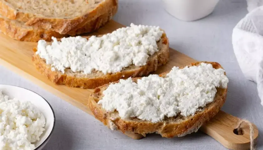Fette di pane rustico con abbondante ricotta fresca, pronte per gustose ricette con ricotta.