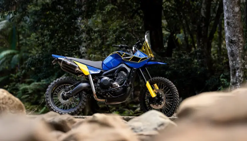 Niebiesko-żółty motocykl tenere 900 gotowy na przygodę w dziczy, z oponami terenowymi i wysokim zawieszeniem.