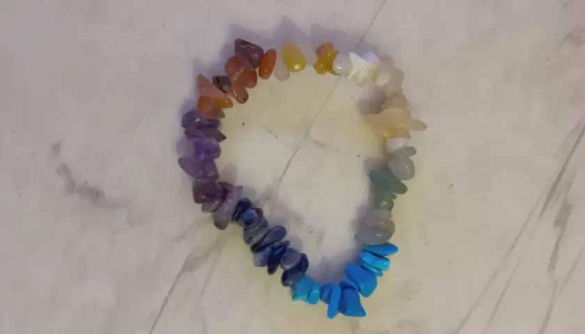 Ett färgglatt chakraarmband med stenar i regnbågens färger, från rött till lila.