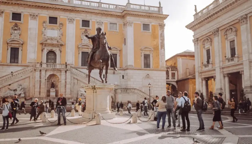 Piazza del Campidoglio a Roma, con la statua equestre di Marco Aurelio e turisti che ammirano l'architettura rinascimentale.