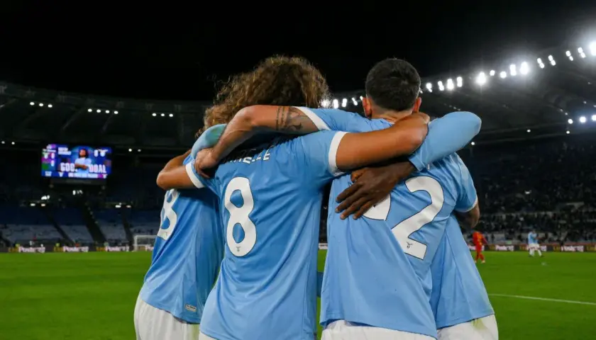Piłkarze Lazio świętują bramkę w meczu z A.C. Milan. Stadion wypełniony kibicami, na tablicy wyników "GOAL".