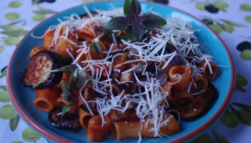Pyszne danie pasta alla norma z makaronem rigatoni, bakłażanem w sosie pomidorowym i startym serem.