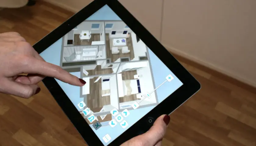 Mit einem Tablet wird die Planung zum Haus einrichten. Eine Person navigiert durch einen 3D-Grundriss, um Möbel zu platzieren und Räume zu gestalten.