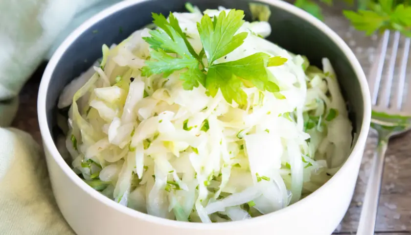 Frischer Krautsalat, perfekt zum krautsalat selber machen. Mit Petersilie garniert, serviert in einer Schüssel.