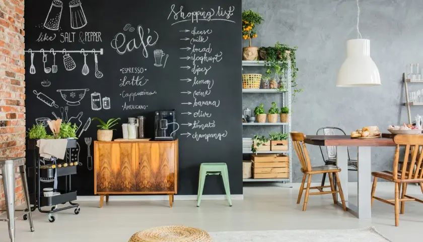 Kreative Ideen für einen kleinen Partyraum: Tafelwand mit Einkaufsliste und Café-Menü, Vintage-Schrank, Pflanzen und Essbereich.