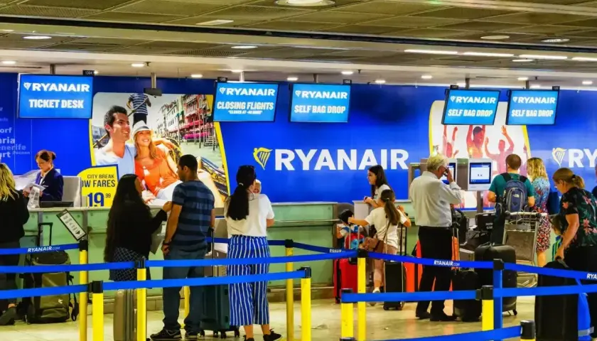 Odprawa na lotnisku Ryanair. Pasażerowie czekają w kolejce do stanowiska odprawy bagażu i biletów.