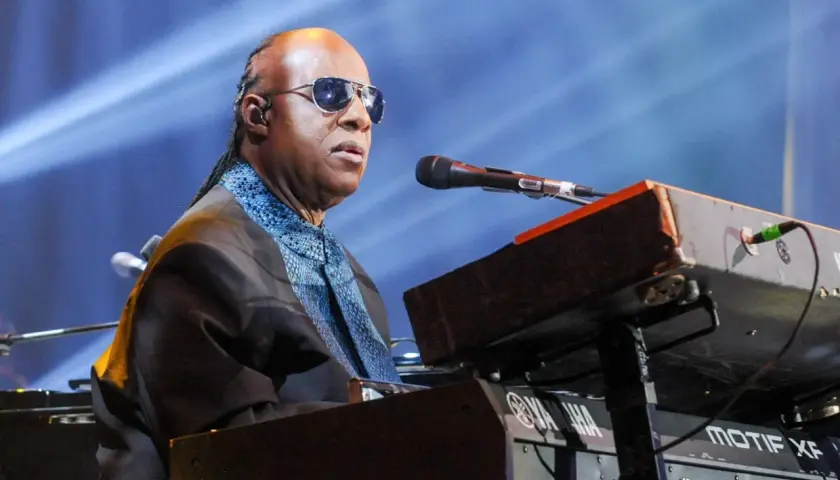 Niewidomy piosenkarz Stevie Wonder gra na keyboardzie Yamaha podczas koncertu.