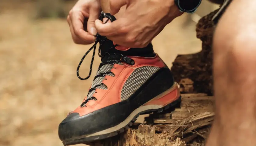 Lacing up sturdy resole hiking boots for an adventure. The orange and black design promises grip and support on any trail.