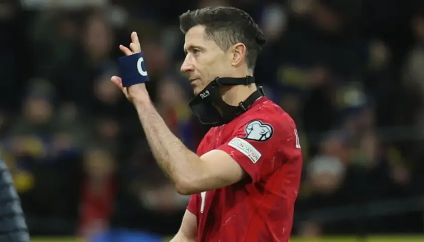 Robert Lewandowski, kapitan kadry, w czerwonej koszulce z opaską "C" na ręce i maską RL9 na twarzy.