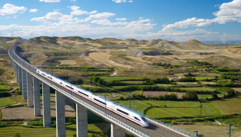 Schneller Zug auf einer Hochbahnbrücke, der die Landschaft von Deutschland nach Spanien durchquert.