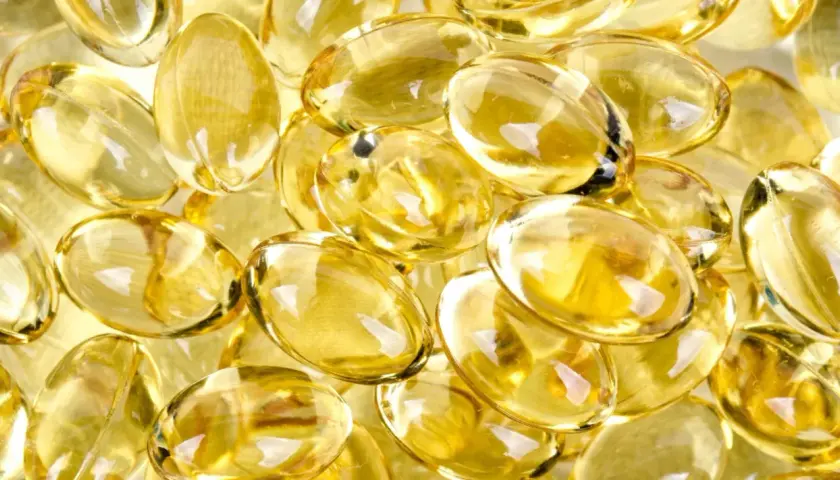 En närbild av genomskinliga, ovala kapslar fyllda med gyllene olja, som påminner om d vitamin-tillskott.
