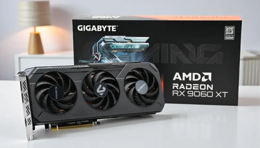 Gigabyte Gaming Grafikkarte mit AMD Radeon RX 9060 XT. Die Karte hat drei Lüfter und die Verpackung ist im Hintergrund zu sehen.