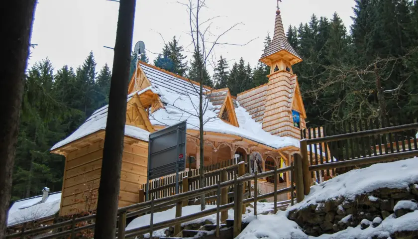Drewniane sanktuarium maryjne na Wiktorówkach w zimowej scenerii, otoczone lasem iglastym.