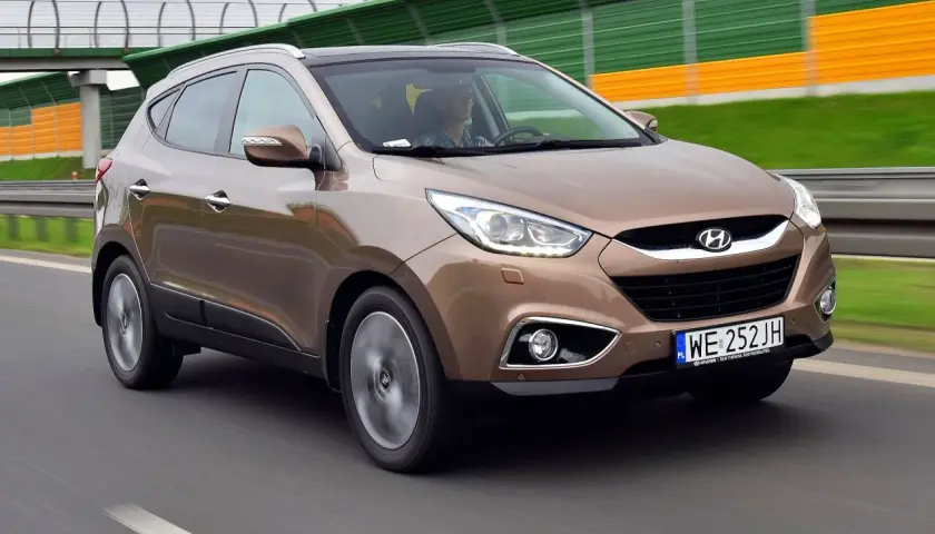 Brązowy Hyundai ix35 w ruchu drogowym, z widocznymi światłami LED i tablicą rejestracyjną WE 252 JH.