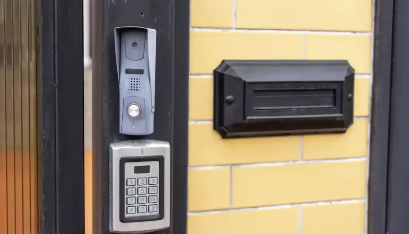 Nowy domofon z klawiaturą kodową i skrzynką na listy na żółtej ścianie bloku.