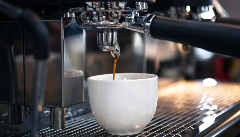 Un espresso scuro gocciola in una tazza bianca. Sorprendentemente, il caffè contiene glutine, un dettaglio che molti ignorano.