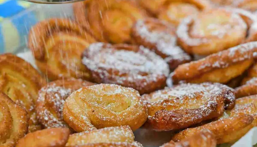 Dolci fritti cosparsi di zucchero a velo, perfetti per il Carnevale. Sembrano deliziosi limoncini, pronti per essere gustati.