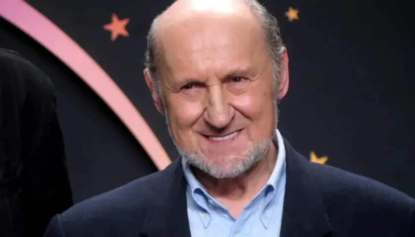 Uśmiechnięty Piotr Fronczewski, znany z wielu niezapomnianych ról w polskich filmach, na tle gwiazd.