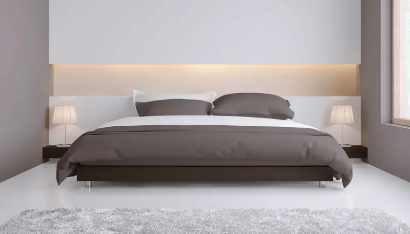Elegante camera da letto con letto moderno e testata letto cartongesso illuminata, comodini con lampade e tappeto soffice.