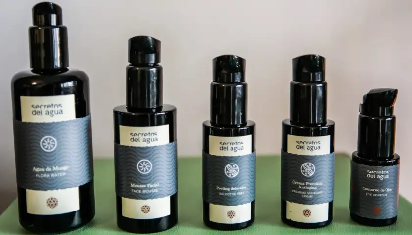 Cinco envases de productos de belleza "Secretos del Agua": agua de musgo, mousse facial, peeling selectivo, crema antiaging y contorno de ojos.