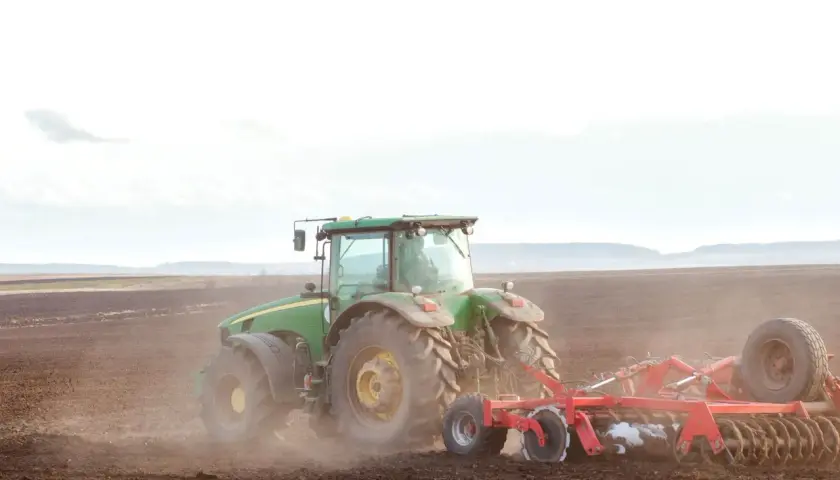 Zielony traktor orze pole. To symbol przekazania gospodarstwa rolnego, które pozwala na opiekę nad rodzicami i dalszy rozwój.