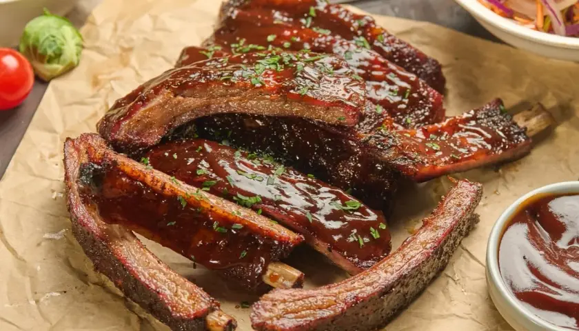 Délicieuses ribs partie du porc, nappées de sauce barbecue et parsemées de persil frais. Un délice à savourer !