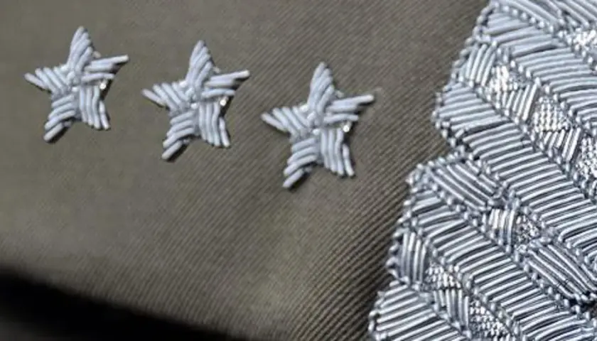 Trzy gwiazdki w wojsku, symbol wysokiej rangi, zdobią mundur obok ozdobnego naramiennika.