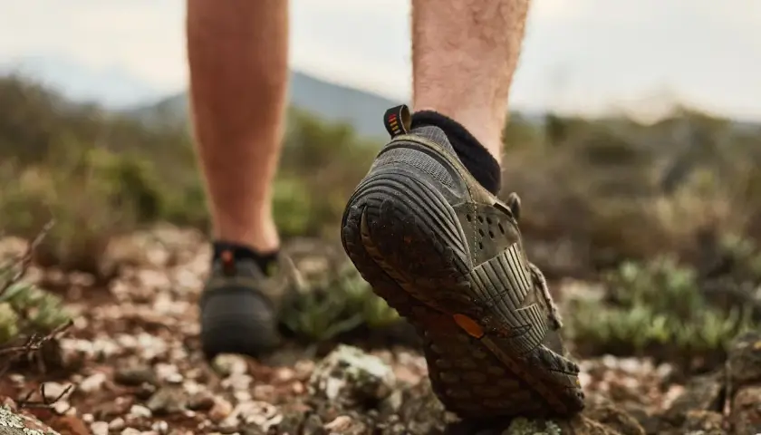 Niski profil butów trekkingowych, z widoczną wysokością cholewki, podczas marszu po kamienistym, suchym terenie.
