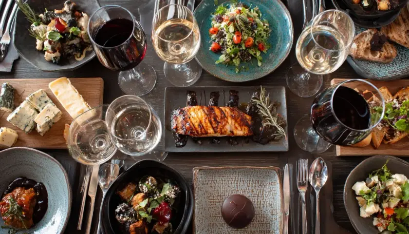 Un verre de pinot noir avec un plat de poisson grillé, accompagné de salades, fromages et desserts.
