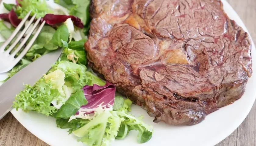 Un savoureux steak côté à l'os, accompagné d'une salade fraîche et colorée. Un délice prêt à être dégusté.