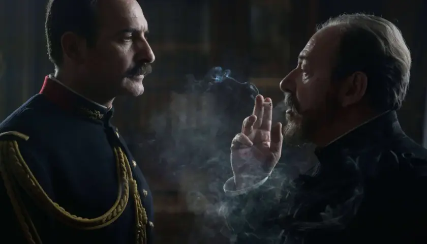 Dwaj mężczyźni w historycznych strojach, jeden w mundurze, drugi z papierosem, w kłębach dymu. Scena z filmu Polańskiego.