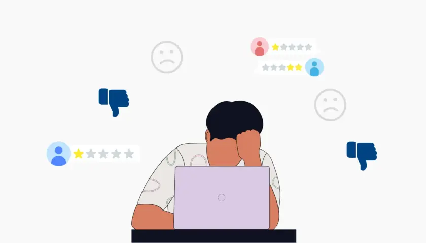 Persona frustrata davanti al laptop, circondata da recensioni negative e pollici in giù. Impara come rispondere alle recensioni negative per migliorare la tua reputazione online.